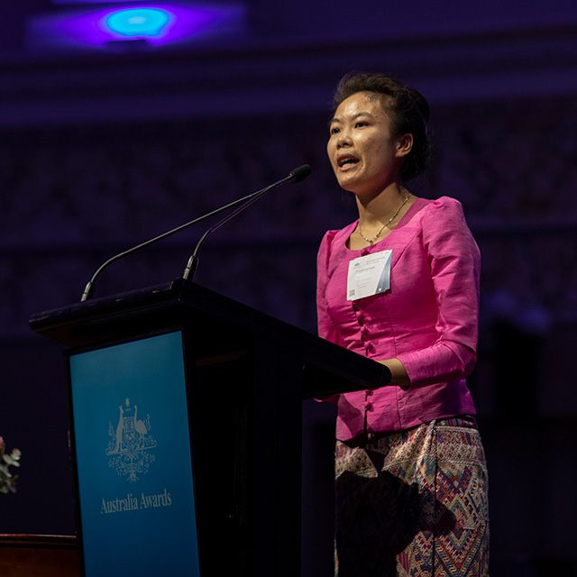 Douangmala speaking up on stage at the Australia Awards lecturn in an official setting. 