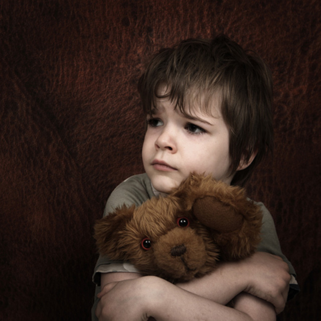caucasian young boy cuddling a teddy bear